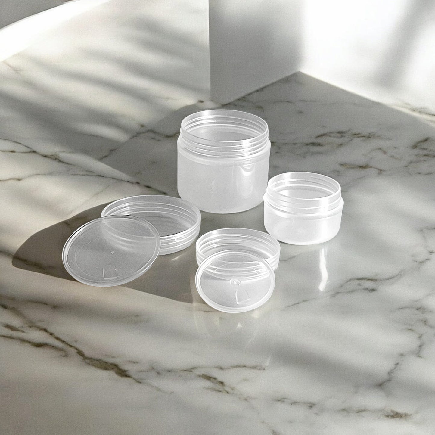 10g and 30g frosted plastic refillable travel pots sitting on a marble surface