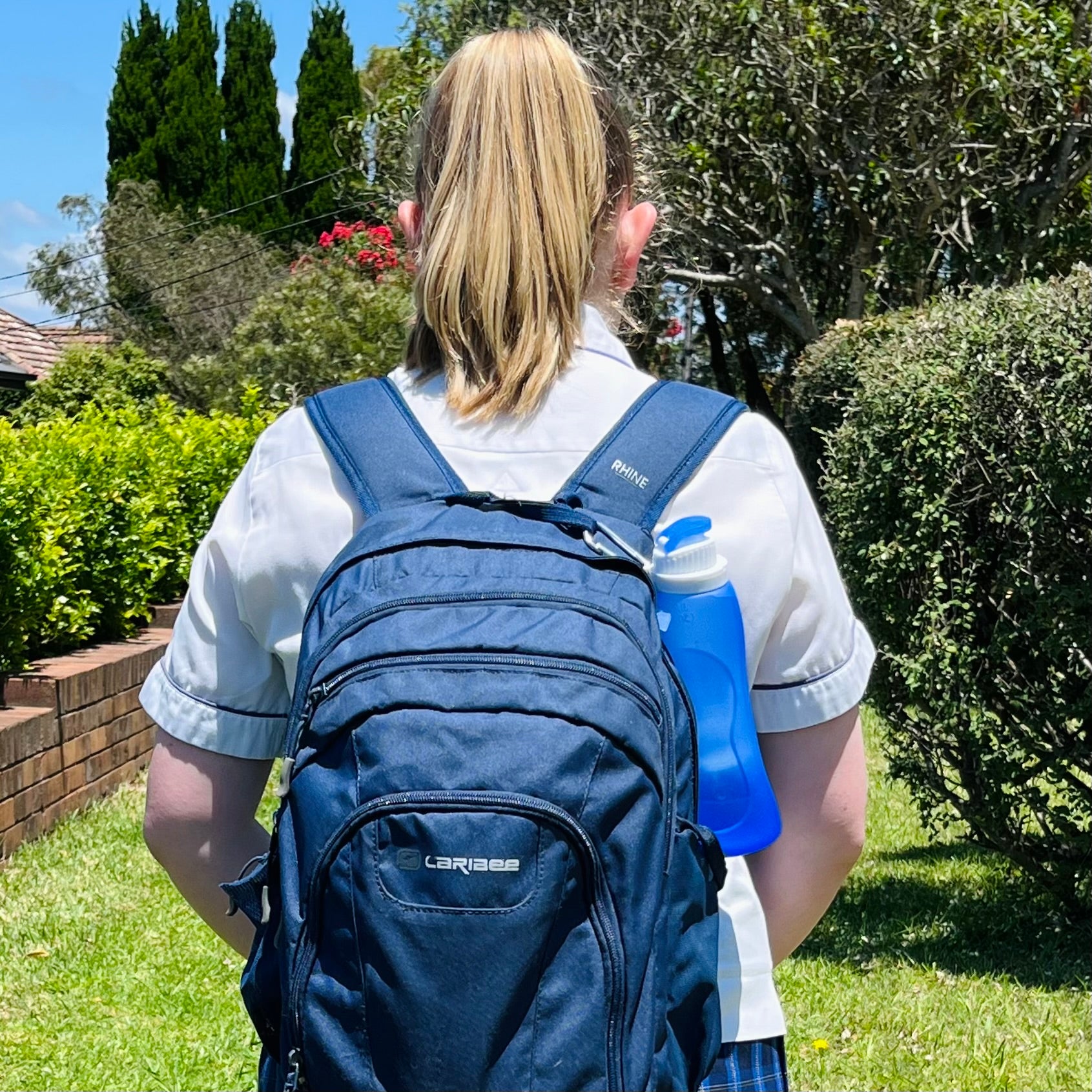  Image of a female walking to school with a Packabel Rollable food grade silicone drink bottle attached to her backpack