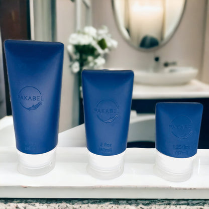 89 ml, 60 ml, and 37ml navy blue refillable food grade silicone toiletry bottles sitting on a bathroom shelf